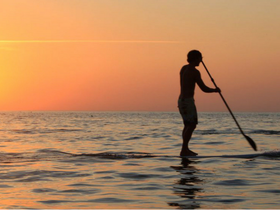 Adolescente practicando paddle surf en Roses al atardecer