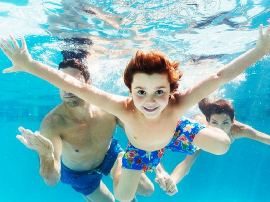 Familia se da un baño en una piscina durante sus vacaciones