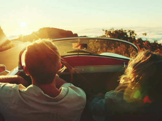 Pareja conduce por una ruta en carretera al atardecer